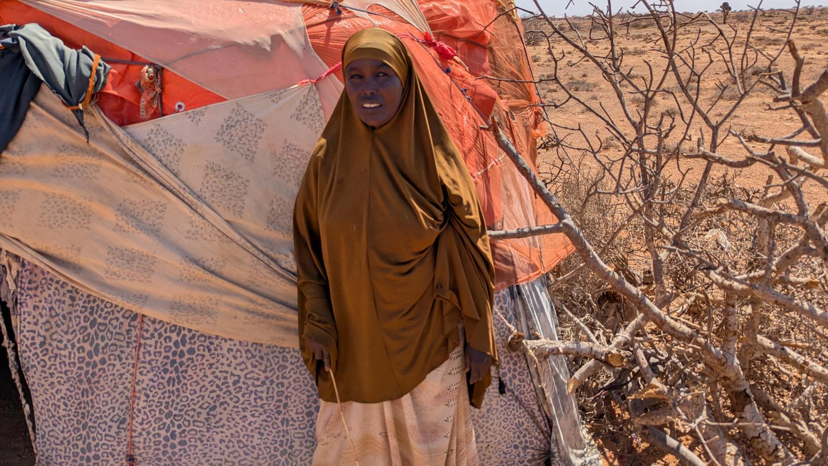 Una mujer frente a su refugio en un campamento de refugiados.