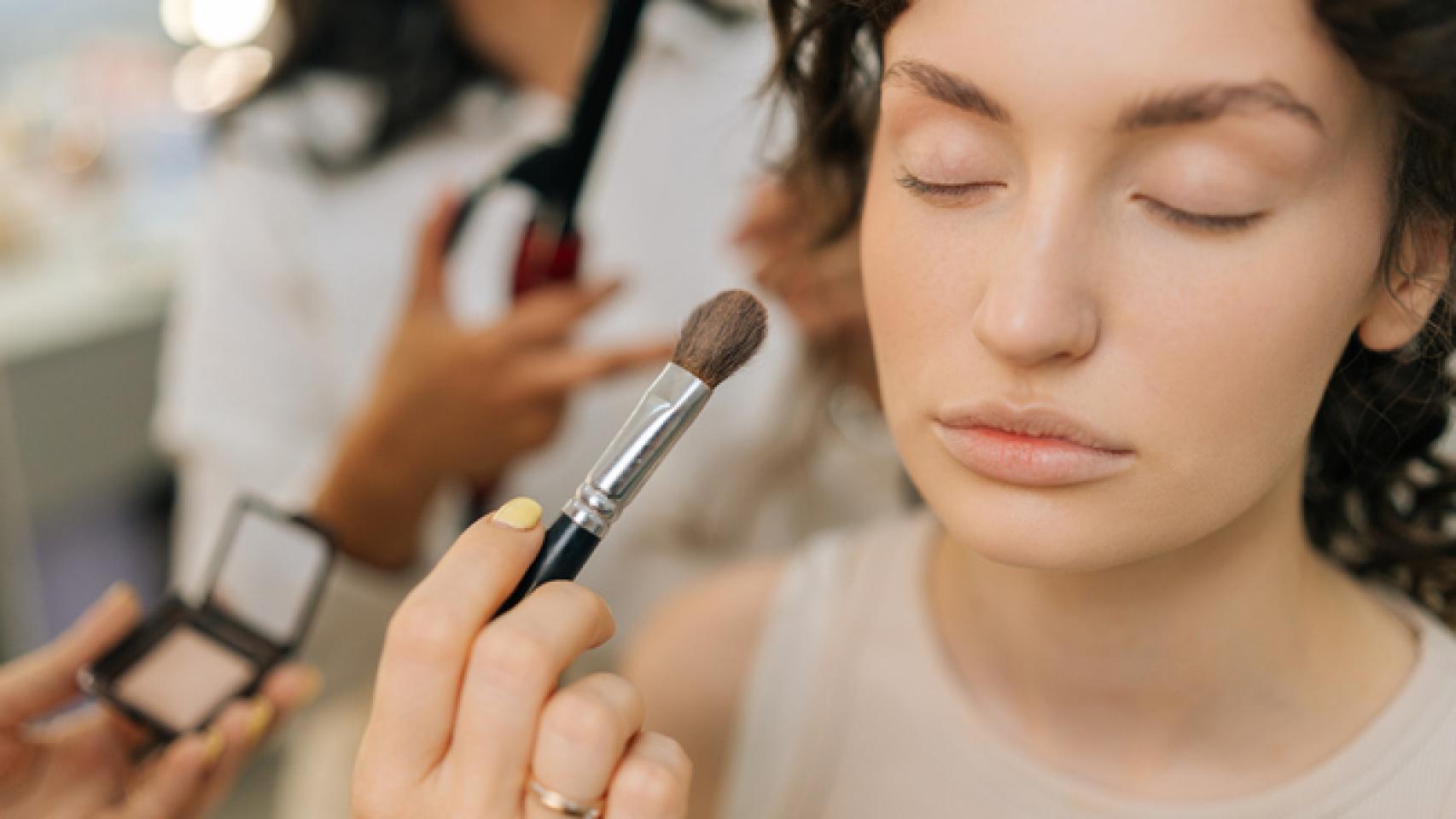 Mujer siendo maquillada por un profesional.