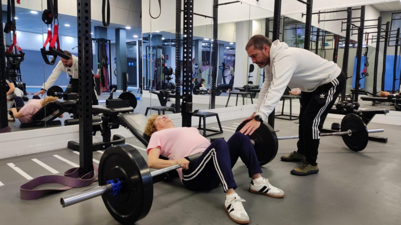 Una usuaria levanta pesas con ayuda de un monitor en el centro de entrenamiento personal JK.