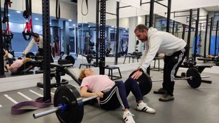 Una usuaria levanta pesas con ayuda de un monitor en JK Entrenamiento Personal.