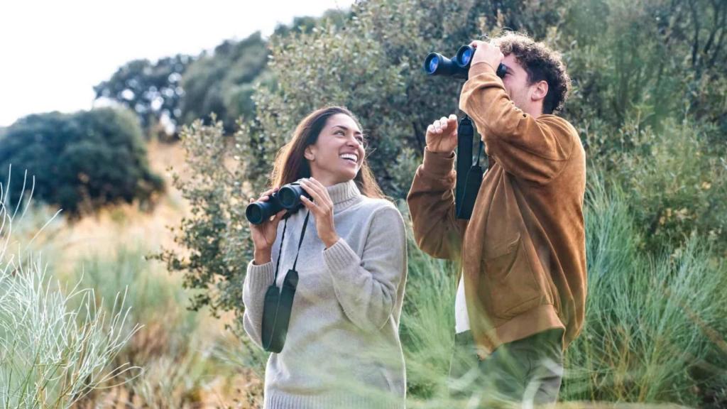 Una pareja observando animales con unos prismáticos.