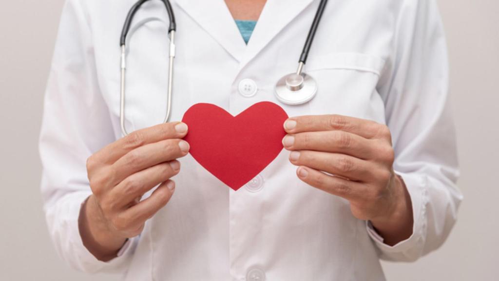 Primer plano de un médico sosteniendo un corazón rojo.