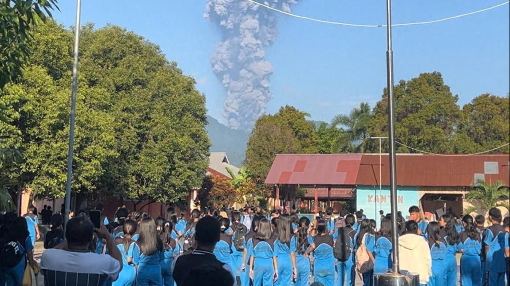 Un grupo de personas observan cómo se eleva el humo tras la erupción del Monte Dukono.