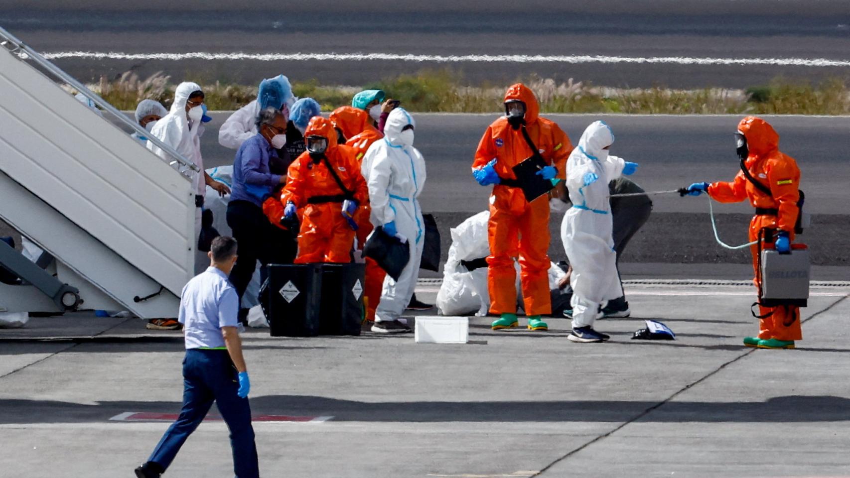 Un pasajero del crucero MV Hondius, afectado por un brote de hantavirus, es desinfectado en la pista del aeropuerto de Tenerife Sur este domingo.