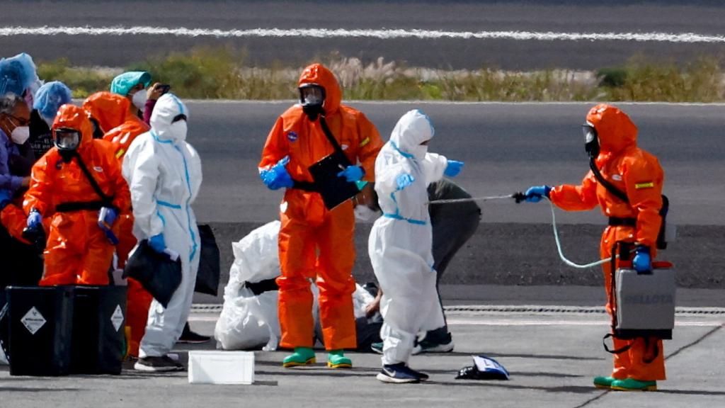 Un pasajero del crucero MV Hondius, afectado por un brote de hantavirus, es desinfectado en la pista del aeropuerto de Tenerife Sur este domingo.