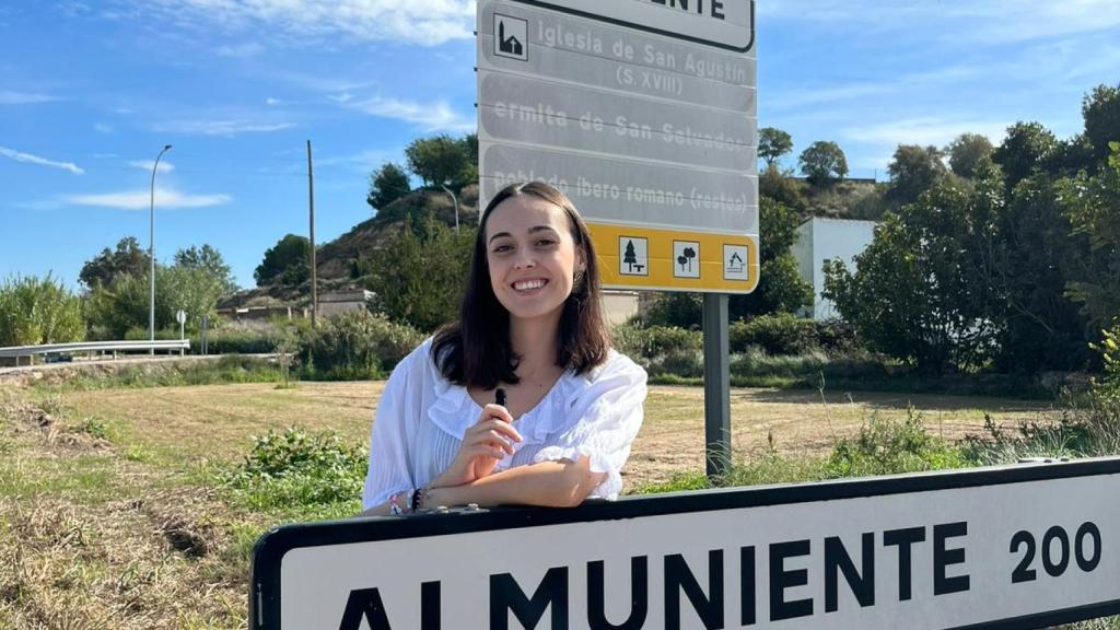 Carla Rivas posa junto al cartel de entrada a su pueblo, Almuniente, durante una de sus grabaciones.