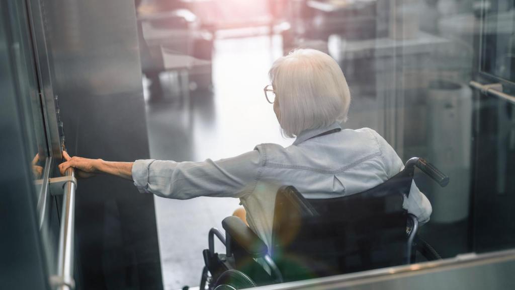 Una anciana subiendo en ascensor, en una imagen de Shutterstock. 