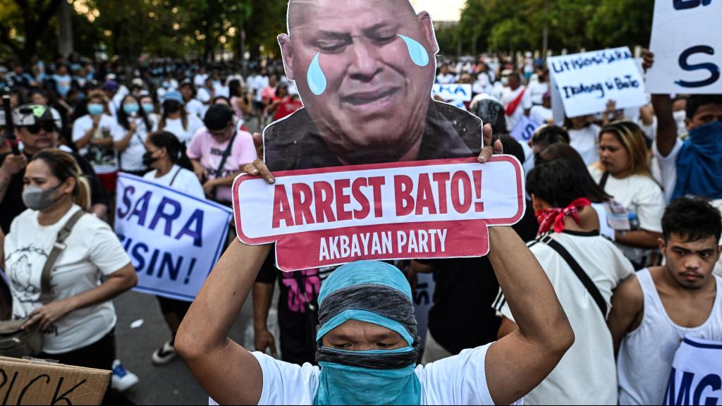 Un activista muestra un cartel con un lema que pide el arresto del senador filipino Ronald Bato dela Rosa durante una protesta frente al Senado de Filipinas.