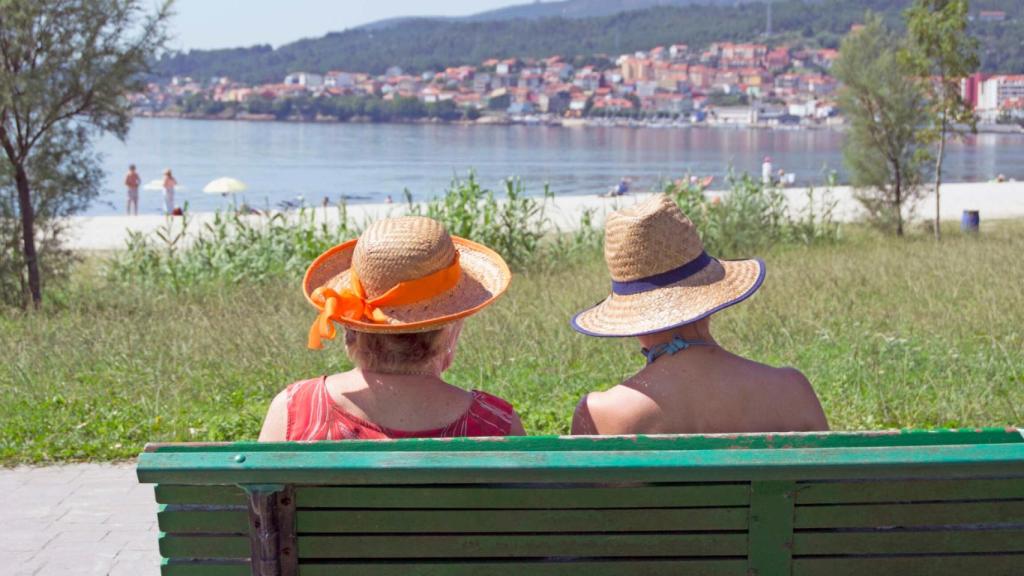 Dos mujeres descansando en el paseo marítimo de la playa de Barraña