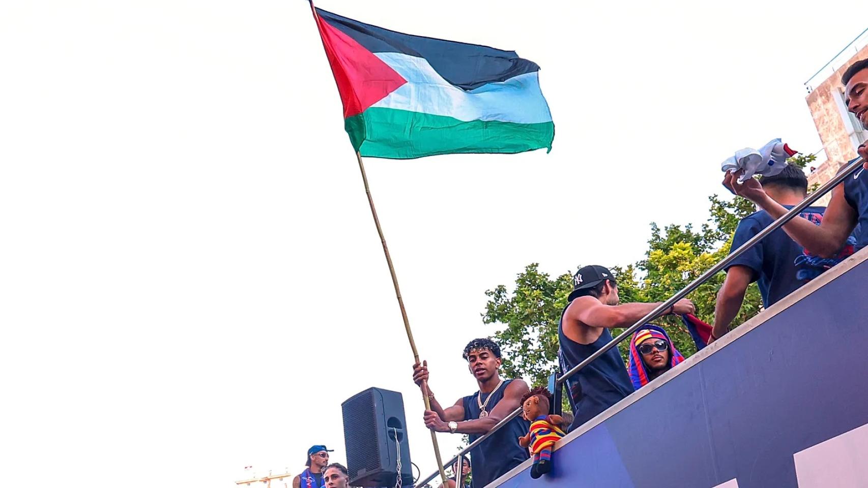 Lamine Yamal ondea la bandera de Palestina durante la rúa del Barça por la ciudad.