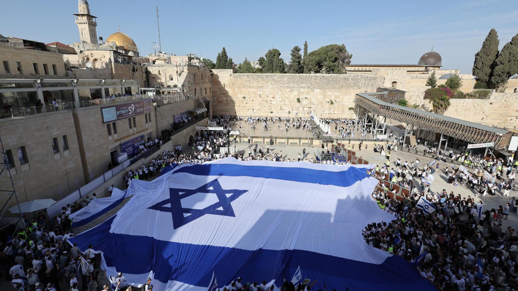 Jóvenes israelíes despliegan una gran bandera israelí en la plaza del Muro Occidental durante las celebraciones del 59.º Día de Jerusalén y la Marcha de las Banderas en la Ciudad Vieja de Jerusalén.