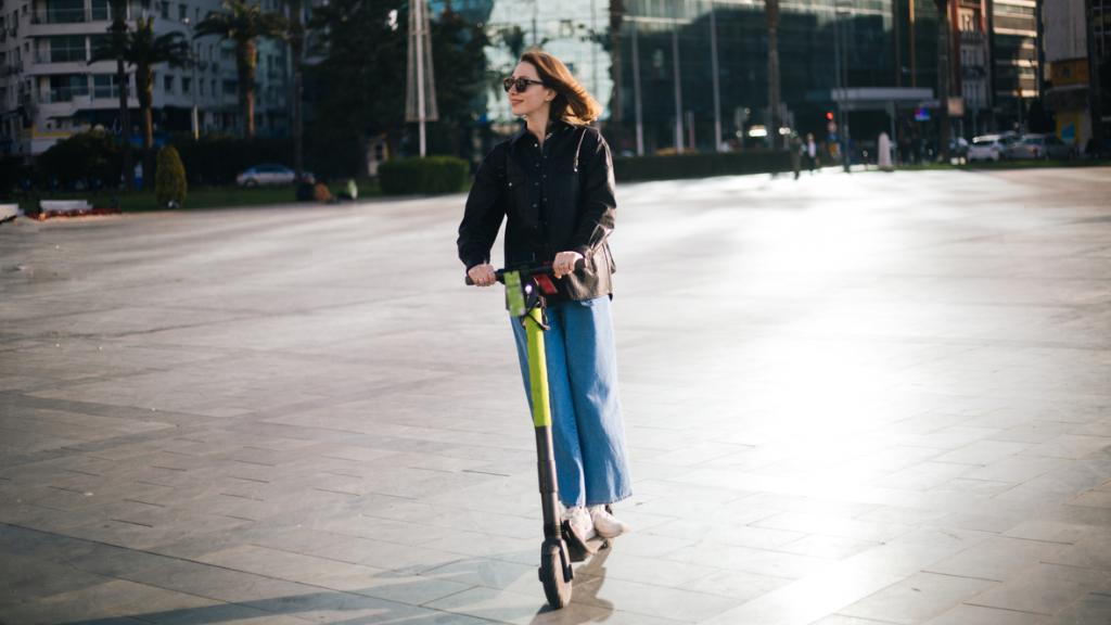 Una mujer montando en patinete eléctrico por el centro de la ciudad. 