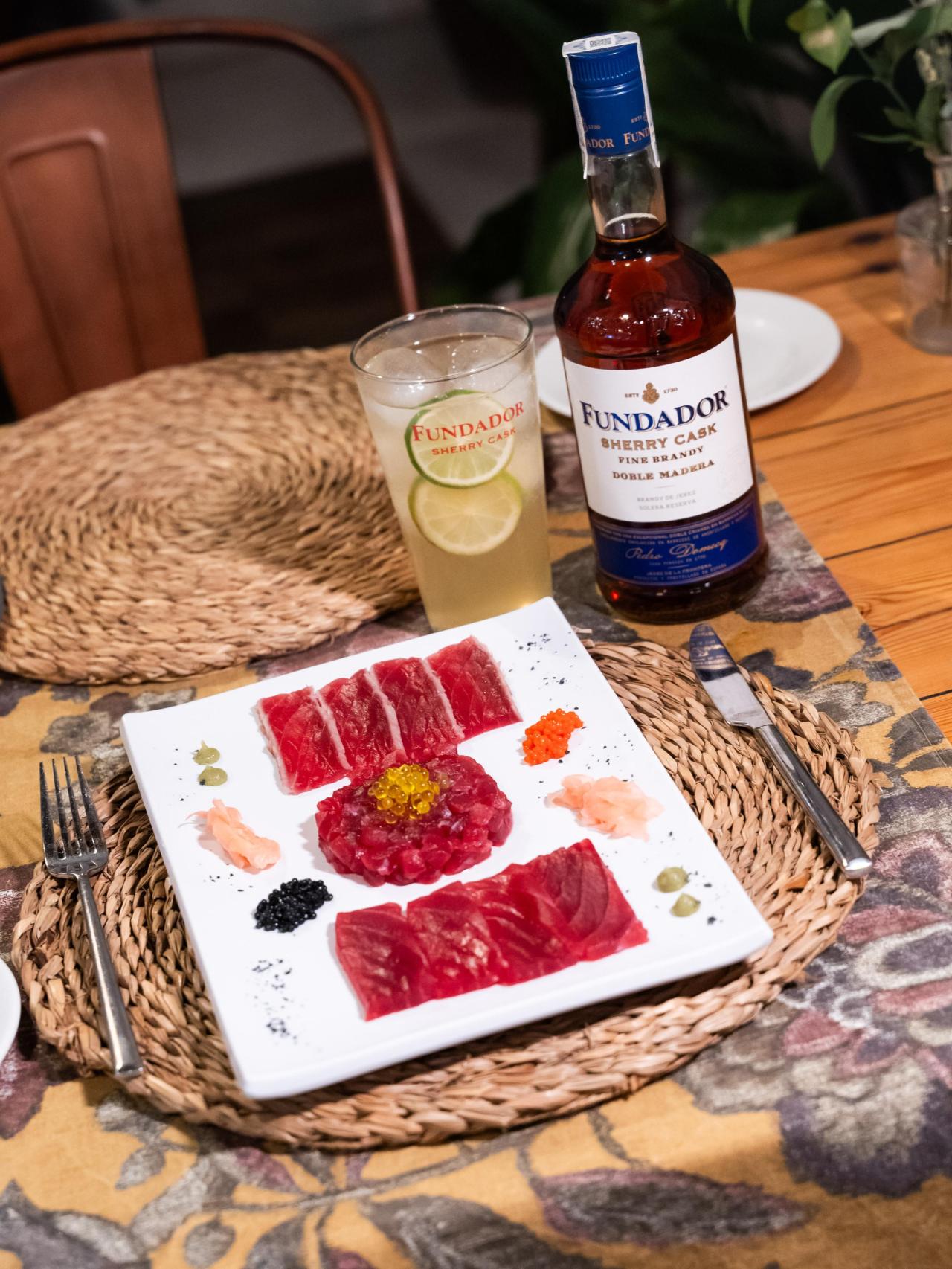 Un plato de atún rojo y una botella de Fundador.