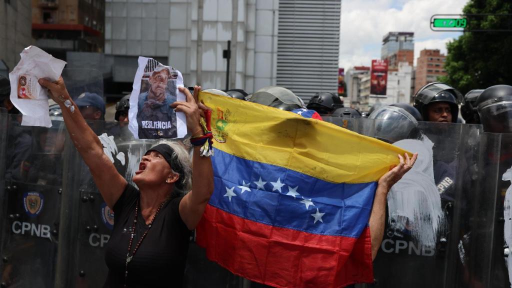 Una persona muestra carteles frente a integrantes del Cuerpo de Policía Nacional Bolivariana.