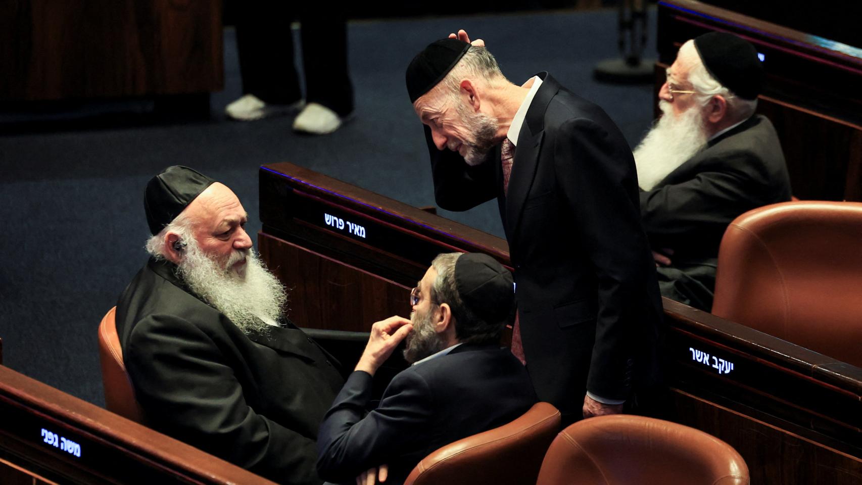 Políticos israelíes reaccionan tras una votación para disolver la Knesset antes de que finalice su mandato, en la sede del Parlamento israelí.
