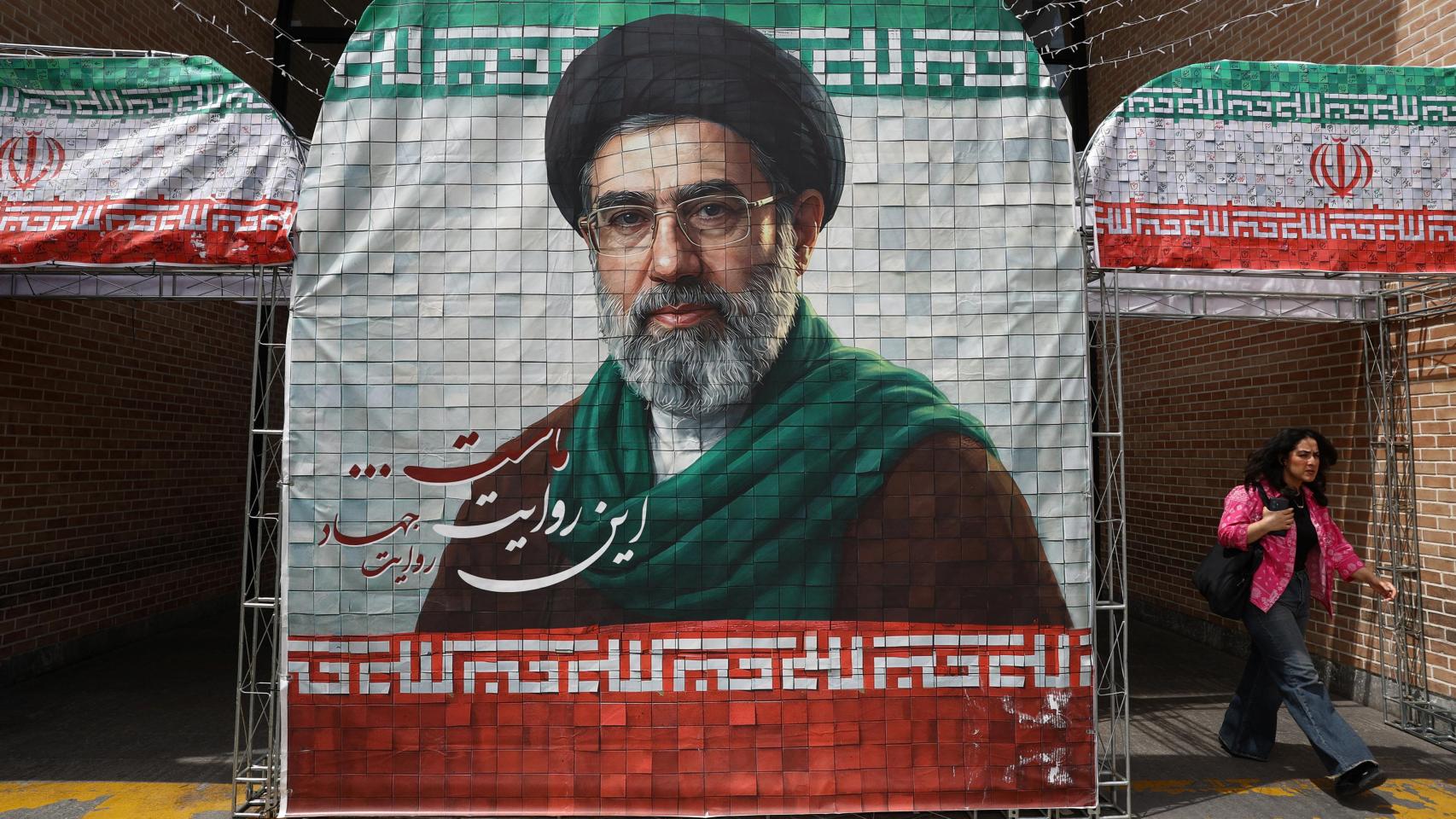 Una mujer pasa al lado de un cartel con la imagen de Mojtaba Jamenei en Teherán.