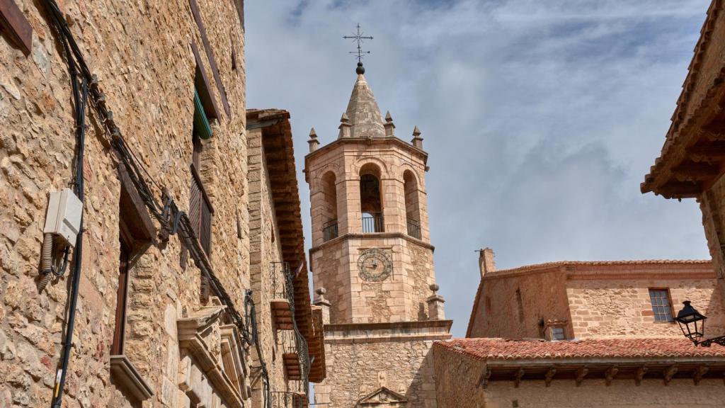 Vista del campanario de la Iglesia de la Asunción en Cantavieja rodeado de edificios históricos de piedra