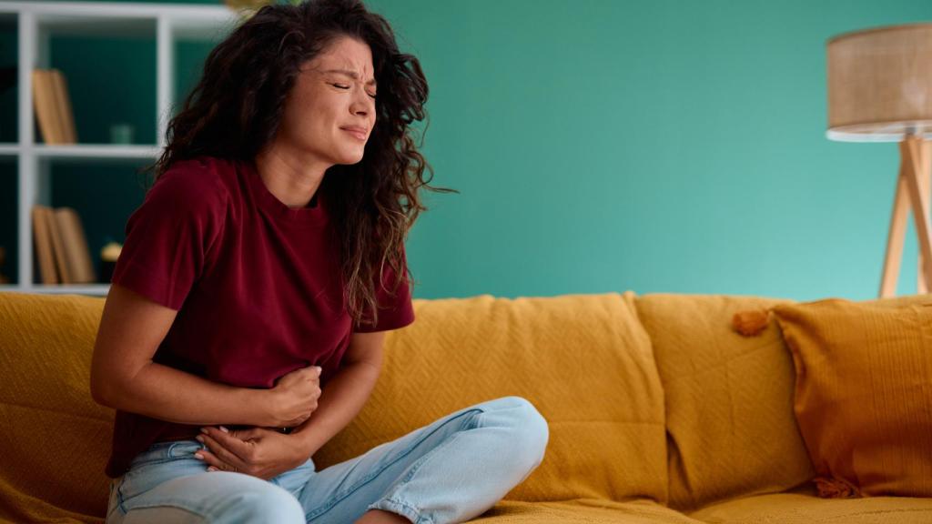 Mujer joven que sufre de fuerte dolor abdominal.