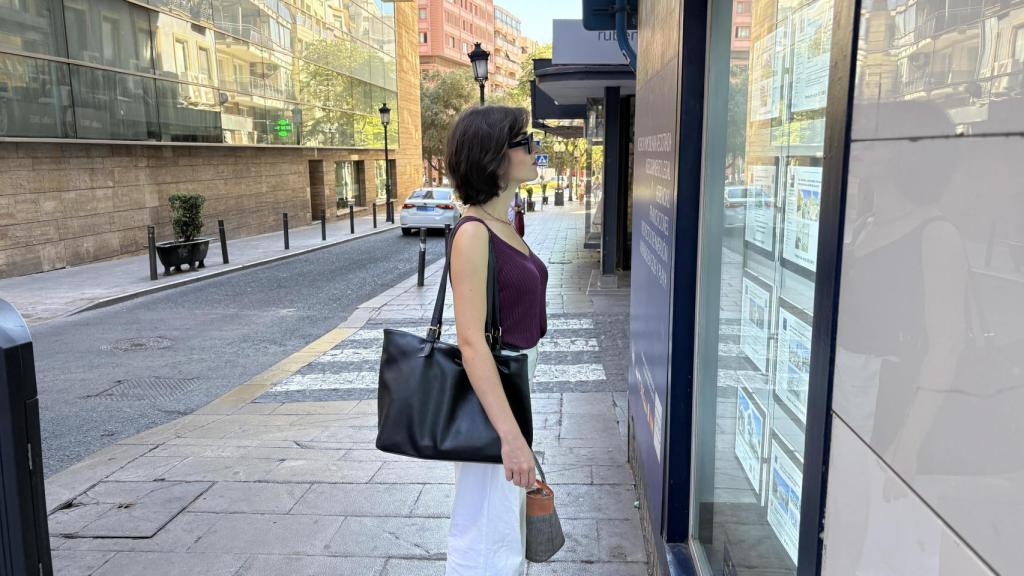 Una mujer mira el escaparate de una agencia inmobiliaria en Alicante.
