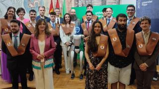 La rectora de la ULE, Nuria González, con los nuevos graduados y el robot Paco
