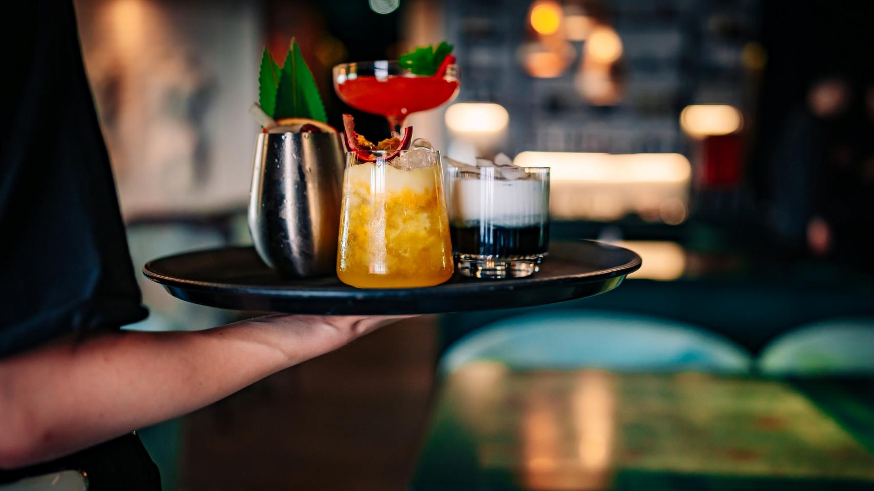 Un camarero sirviendo cócteles en un bar de copas