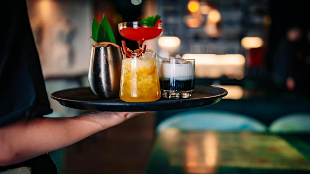 Un camarero sirviendo cócteles en un bar de copas