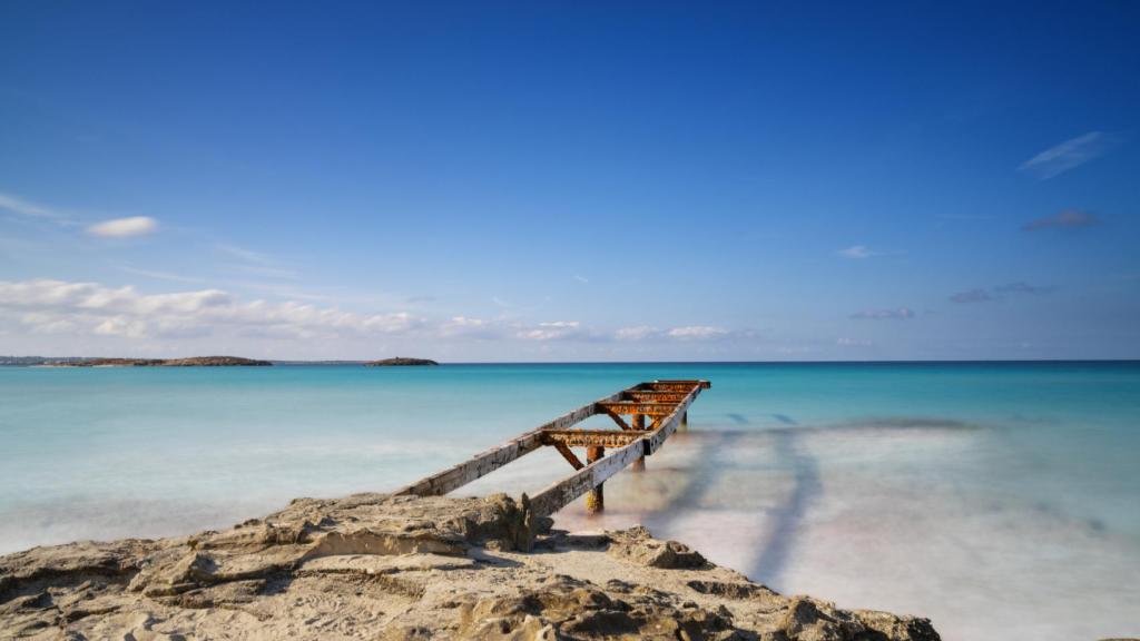 El antiguo muelle se adentra en las aguas turquesas de la playa de Ses Illetes, en el norte de Formentera