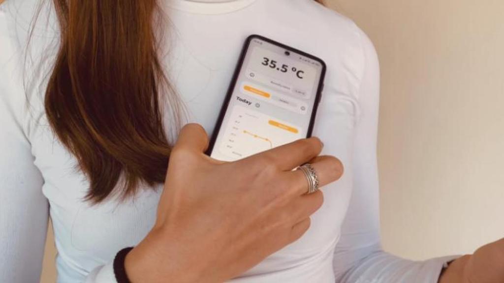 Una mujer acerca el teléfono móvil al chip para conocer su temperatura.