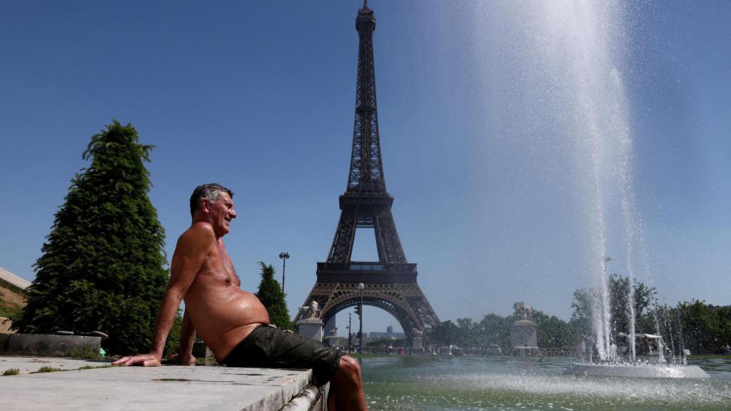 Un hombre se refresca frente a la Torre Eiffel durante la ola de calor en Francia de mayo de 2026. 