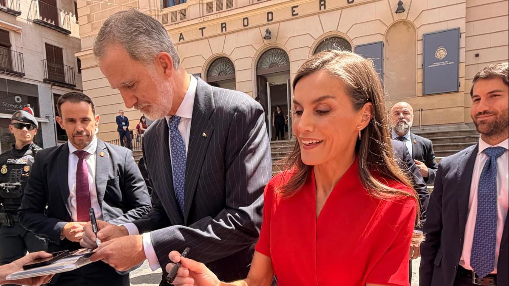 Rey Felipe VI junto a la reina Letizia firmando fotografías del público.