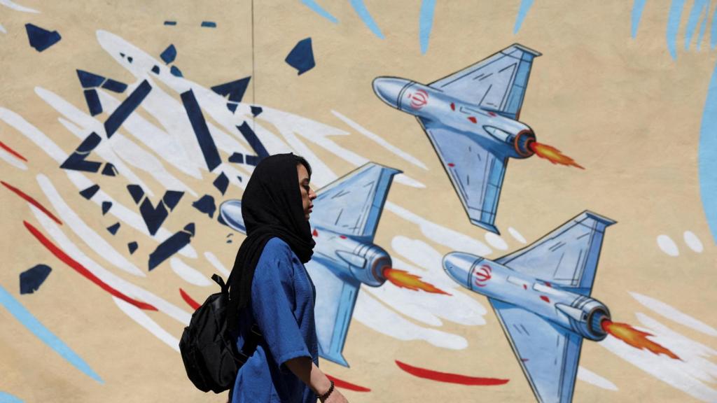 Una mujer iraní camina junto a un mural antiisraelí en una calle de Teherán.