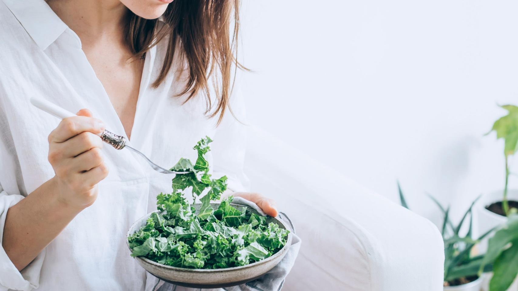 Una mujer comiendo vegetales.