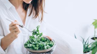 Una mujer comiendo vegetales.