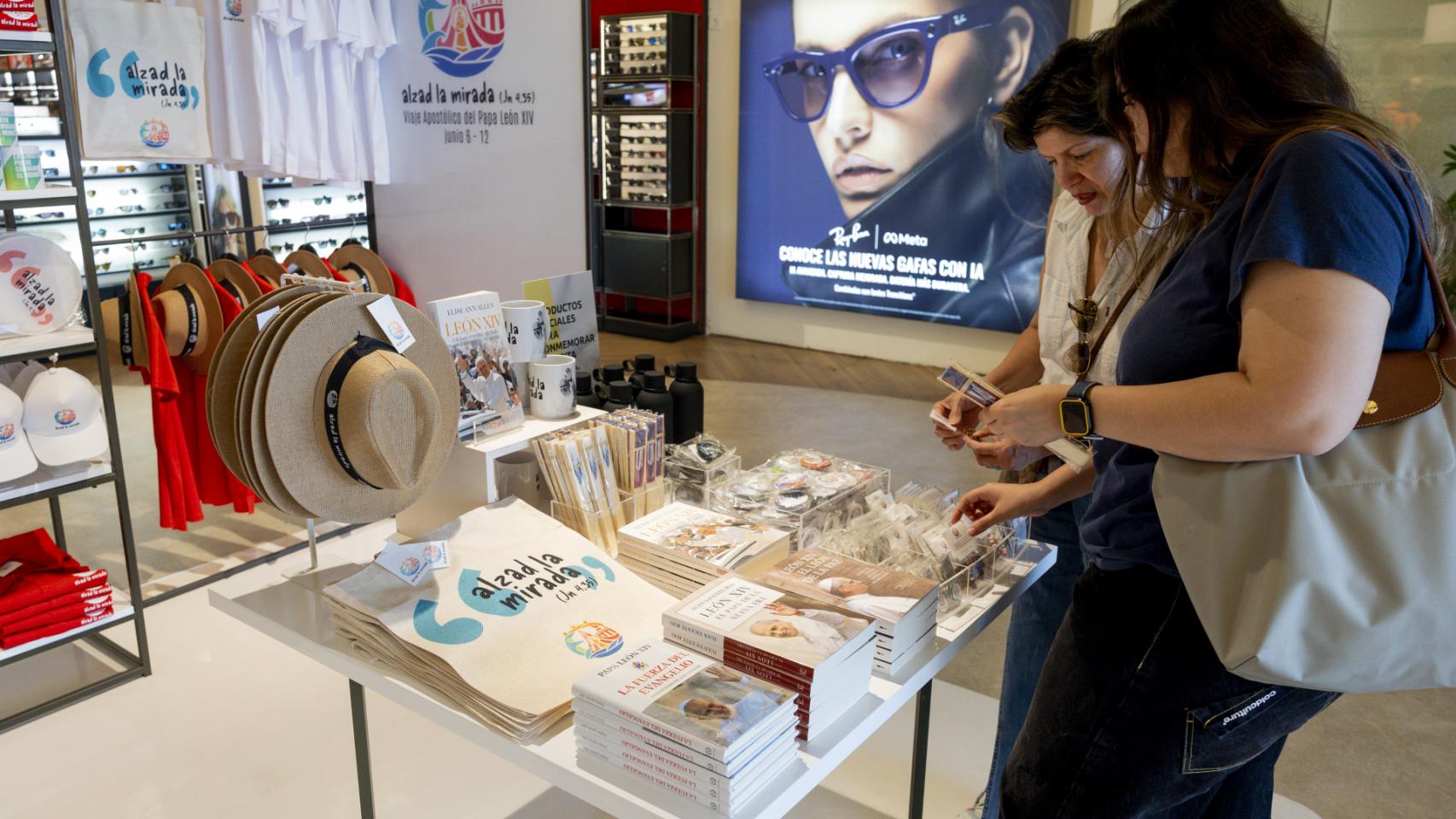 Dos mujeres mirando los productos de merchandising de la visita del Papa a Madrid en El Corte Ingles de Castellana.