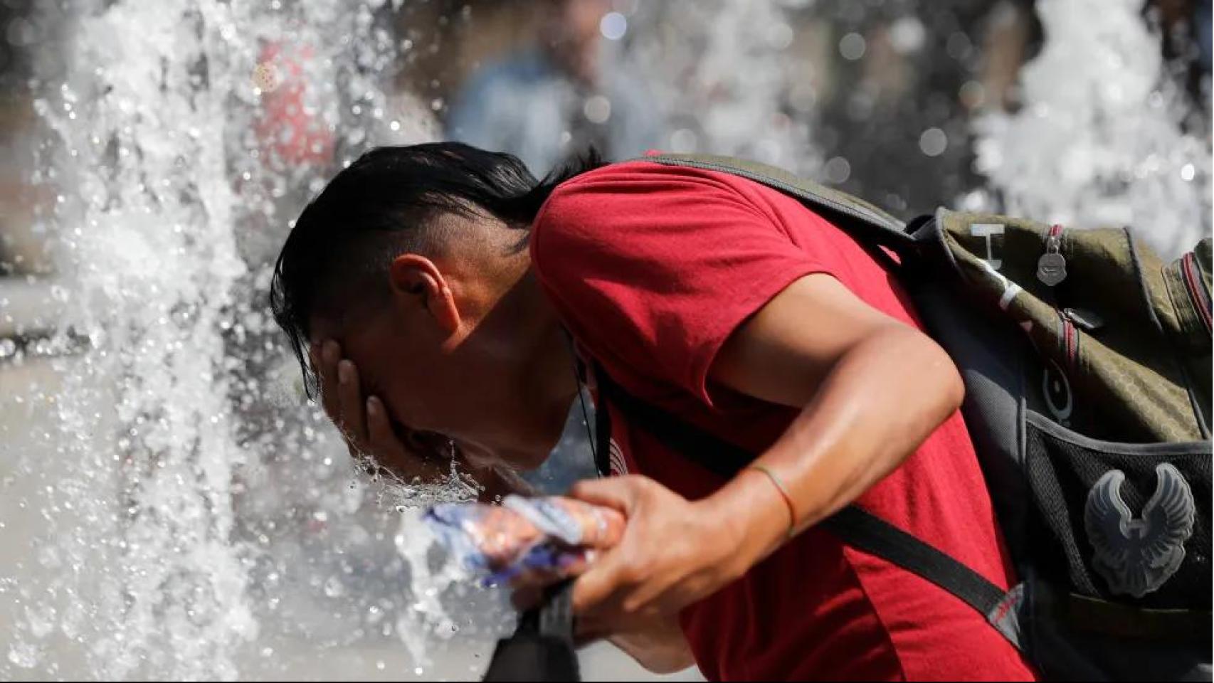 Un hombre se refresca en una fuente debido a las altas temperaturas en Ciudad de México.