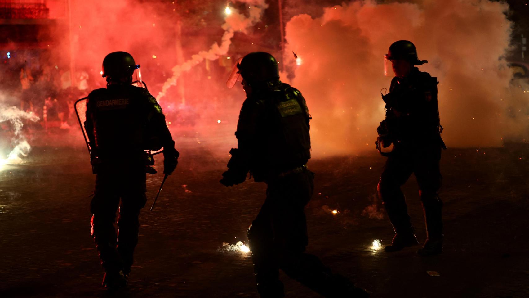 Agentes de la Policía se protegen de las bengalas, en las calles de París este sábado.