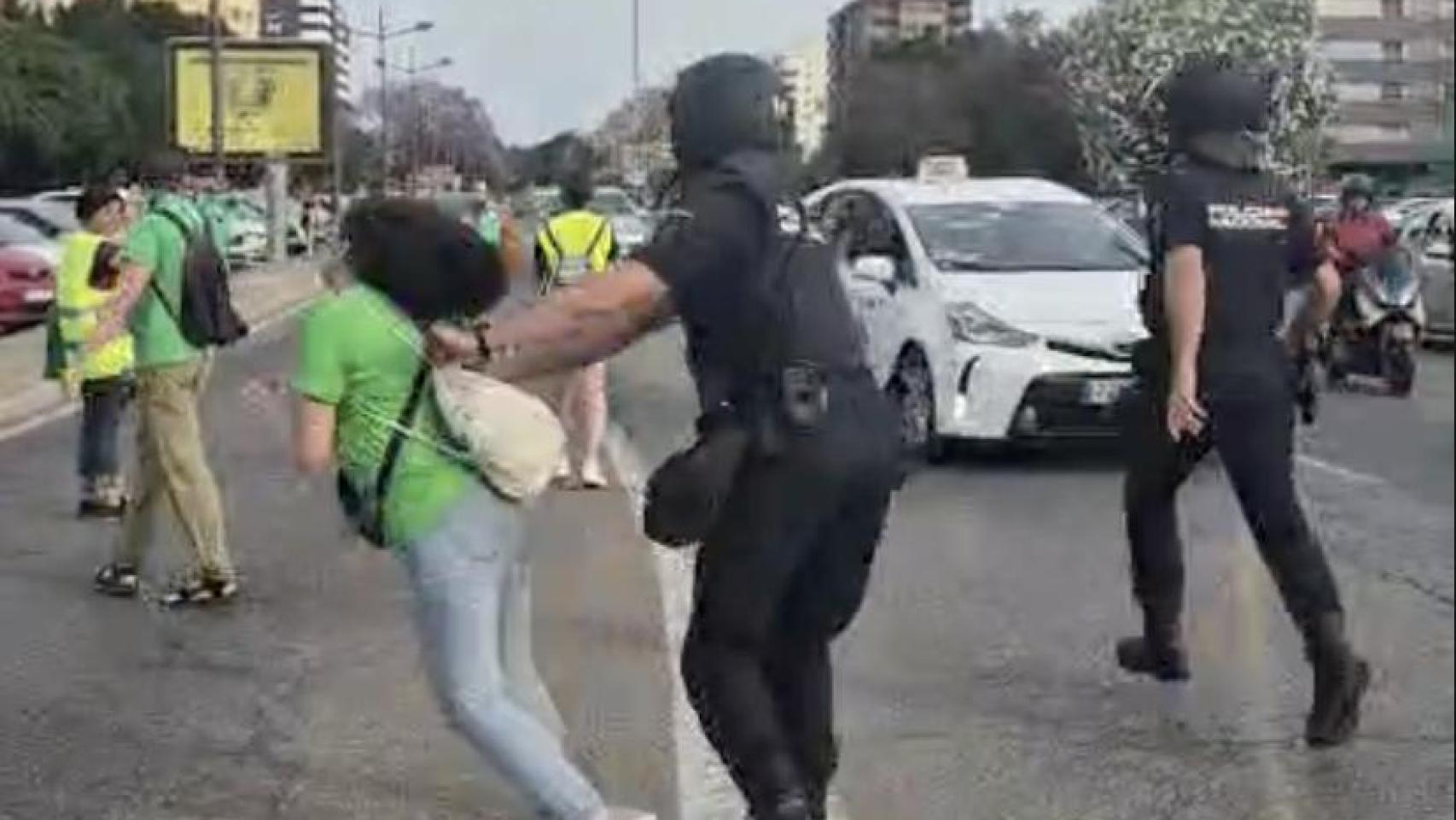 El policía empujó a la manifestante y la tiró al suelo. EE