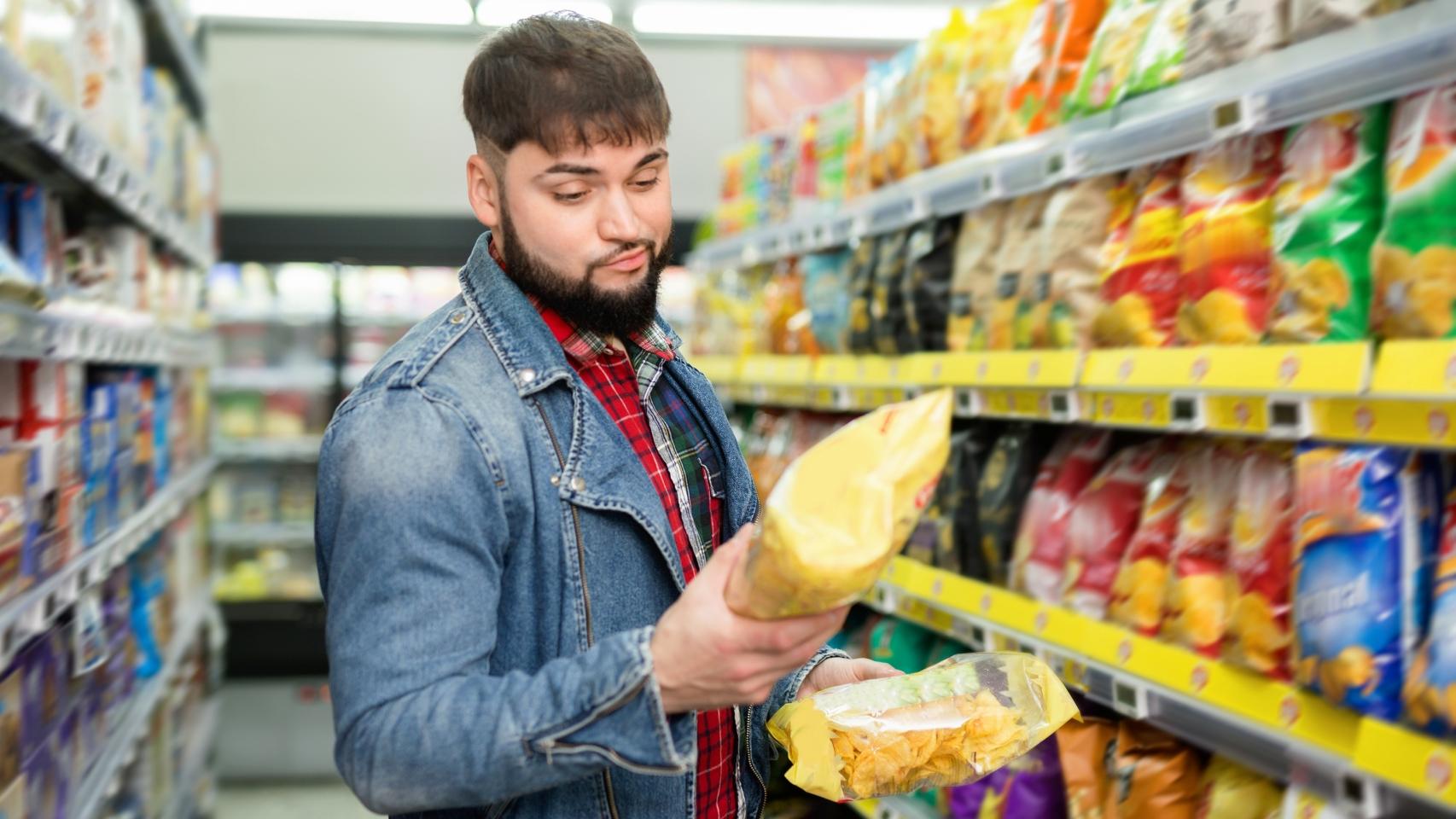 Una persona compara bolsas de patatas fritas en el supermercado