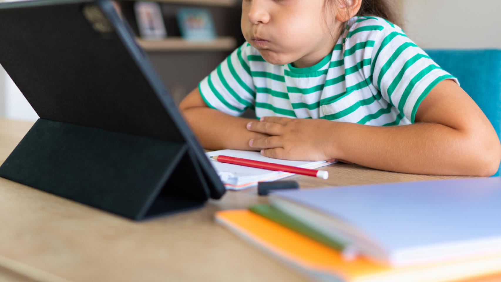 Una niña haciendo los deberes en una tablet.
