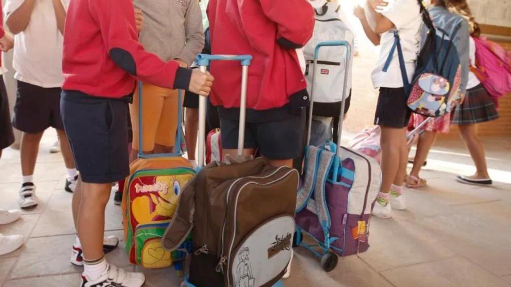 Niños junto a sus mochilas en el colegio. EFE
