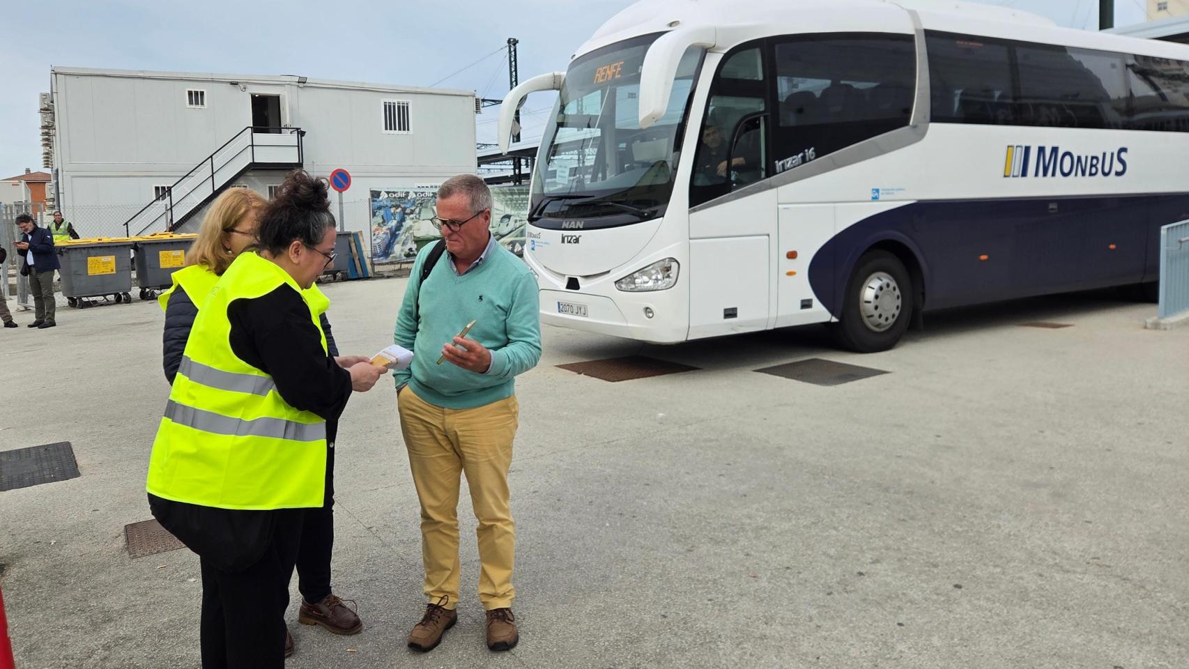 Pasajero preguntando por los cortes de trenes en la estación de A Coruña con un bus alternativo de fondo