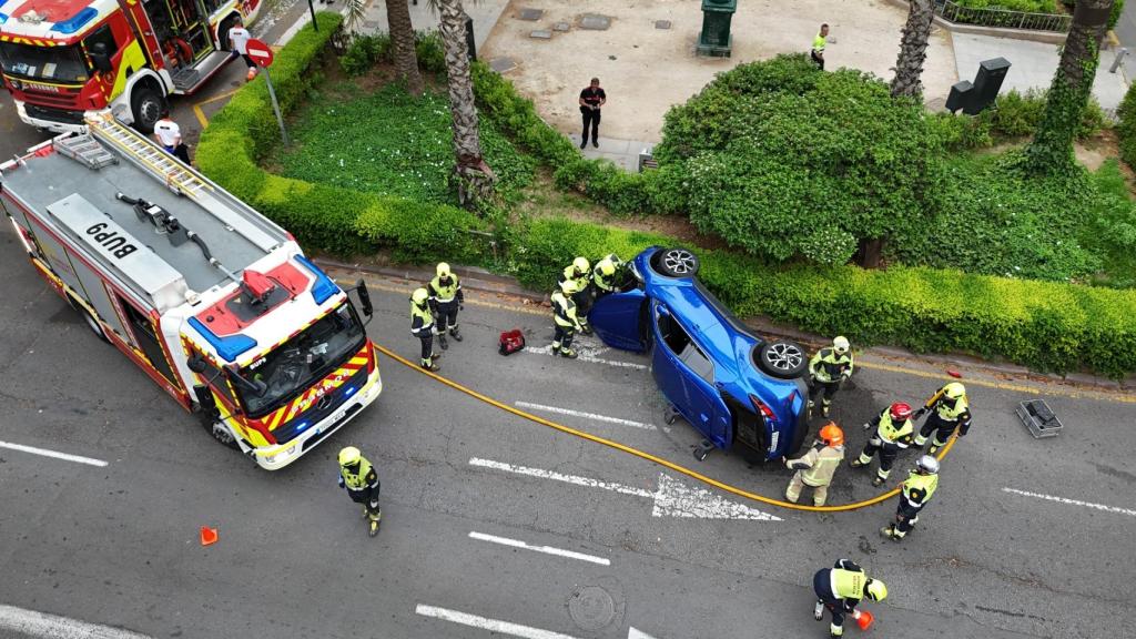 Los bomberos rescatan en Valencia a una conductora tras volcar su coche en la Gran Vía. EE