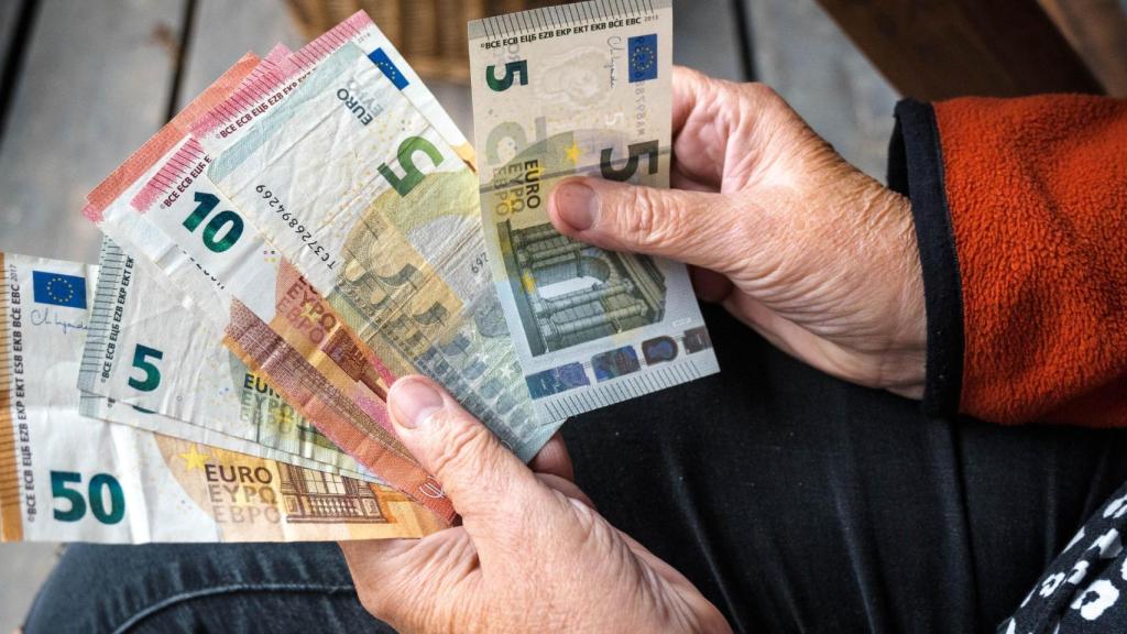 Una persona mayor con varios billetes en la mano