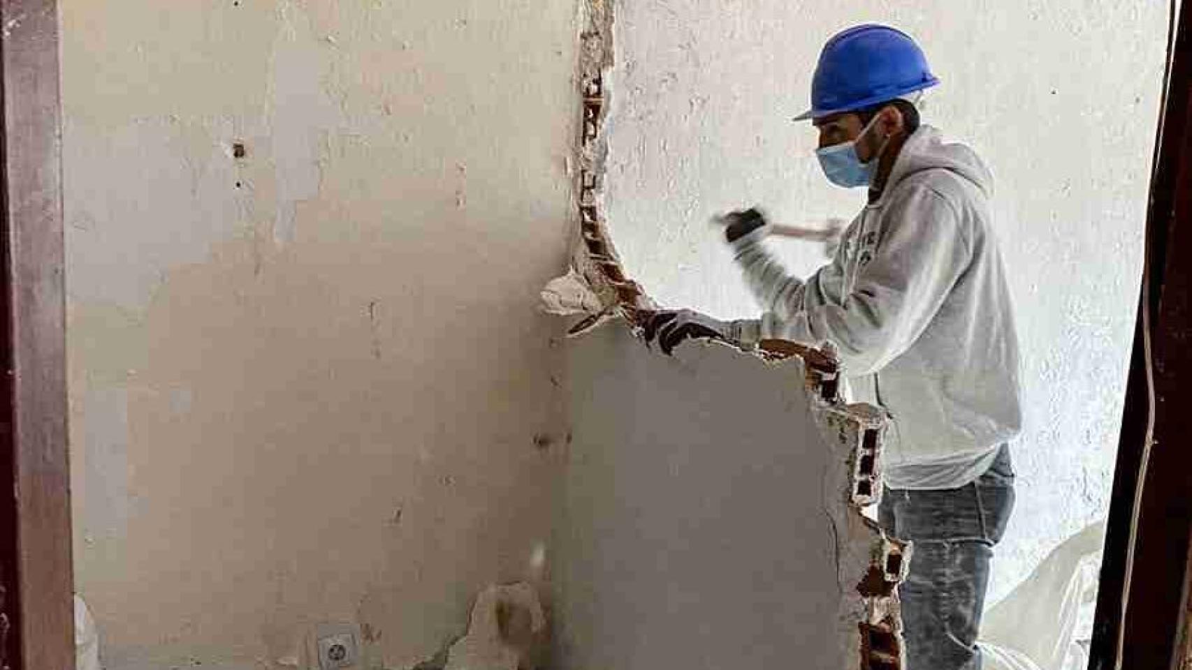 Un obrero tirando una pared en un piso.