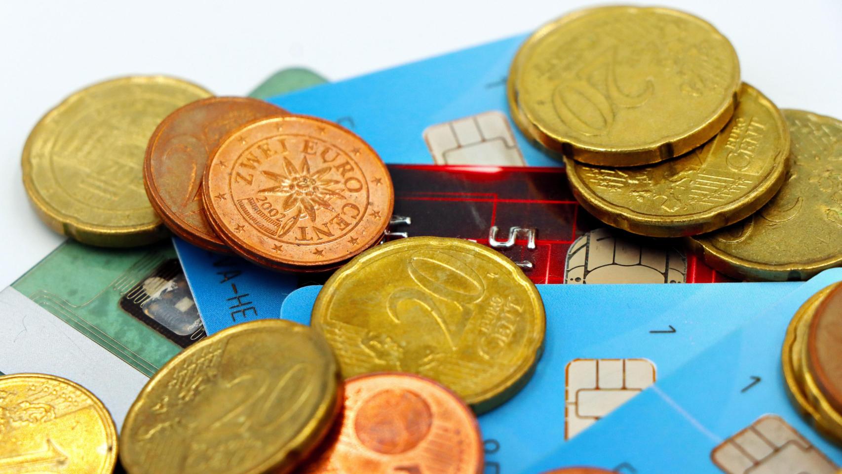 Tarjetas de crédito junto a monedas de euro de distintos países.