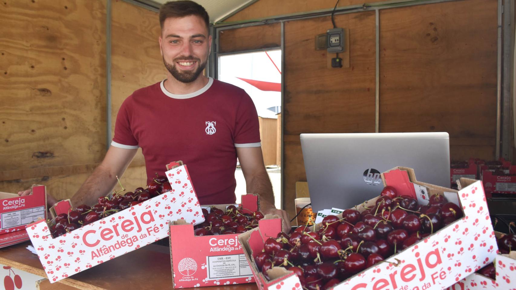 Un joven vendedor de cerezas posa sonriente durante la fiesta