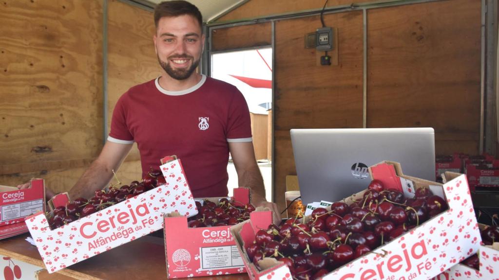 Un joven vendedor de cerezas posa sonriente durante la fiesta