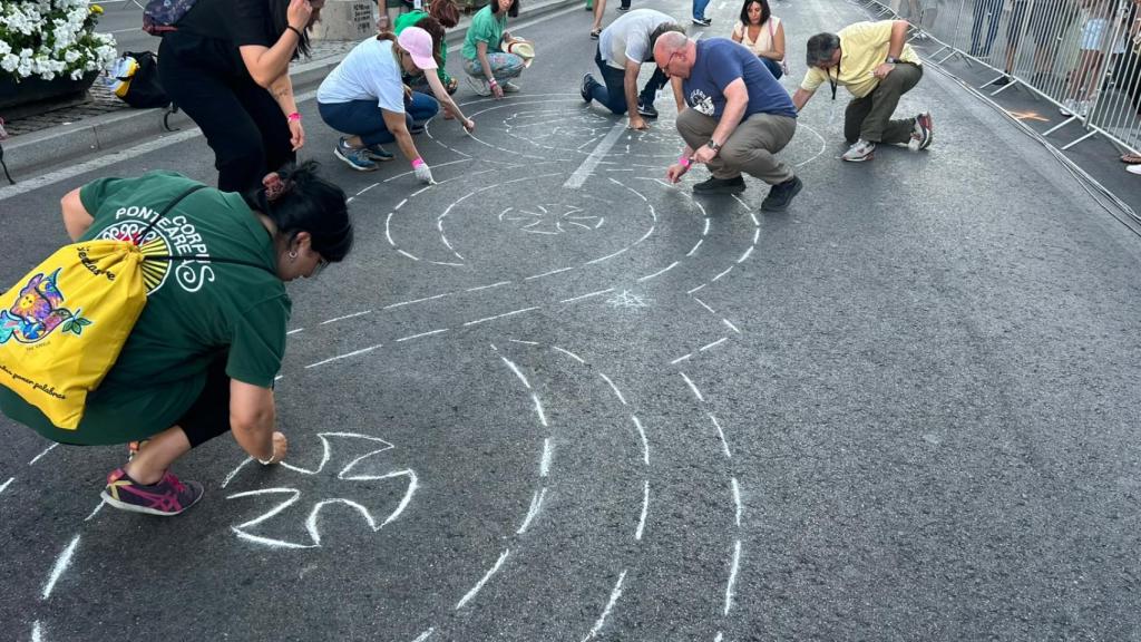 Varios voluntarios realizando el trazado con tiza de las alfombras florales para el Papa.