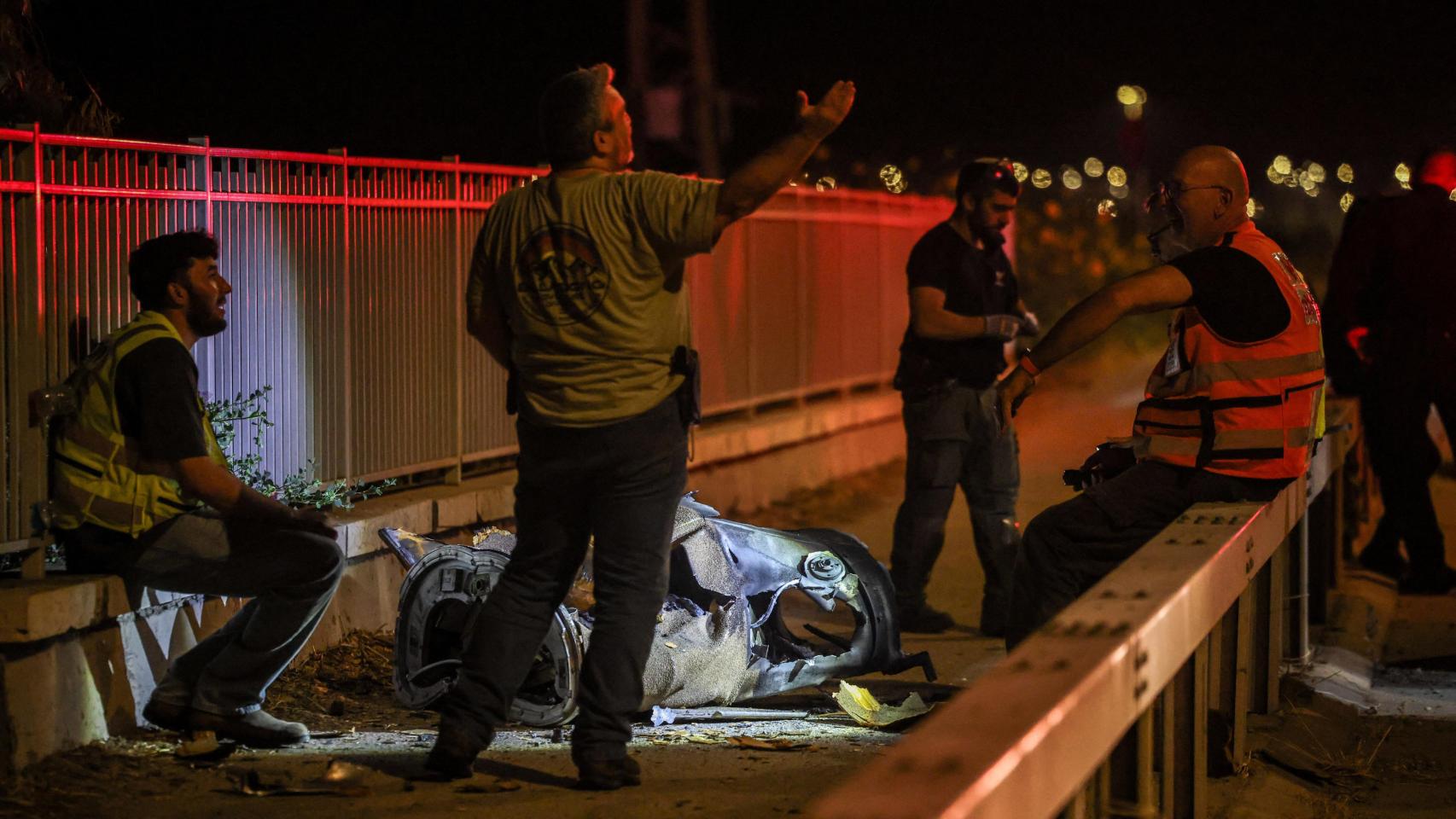 Personal de seguridad y rescate israelí trabaja junto a un fragmento de un proyectil tras un ataque con misiles lanzado desde Irán a Israel.