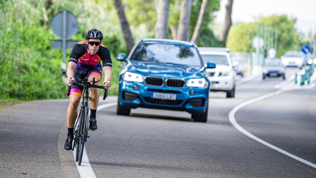 Ciclista en bicicleta en una carretera con tráfico.